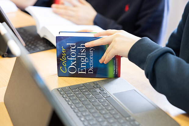 Ein Schüler sitzt im Unterricht mit einem Ipad und Buch im Phorms Gymnasium Hamburg