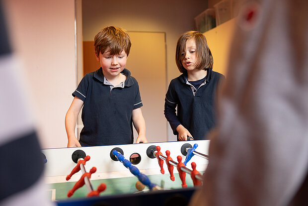 Schüler stehen am Kicker Tisch und spielen gemeinsam in der Phorms Grundschule Hamburg