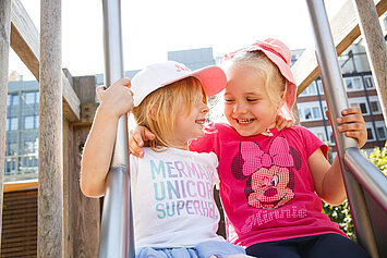 Kinder rutschen gemeinsam auf dem Spielplatz in der Phorms Kita Hamburg
