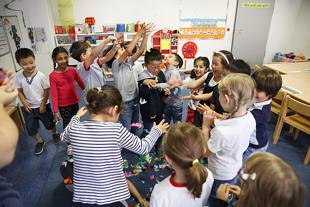 Eine ganze Gruppe Kinder werfen Federn in die Luft in der Phorms Reception Hamburg