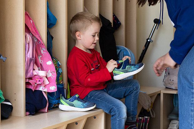 Kita-Kind zieht sich die Schuhe an in der Phorms Kita in Hamburg