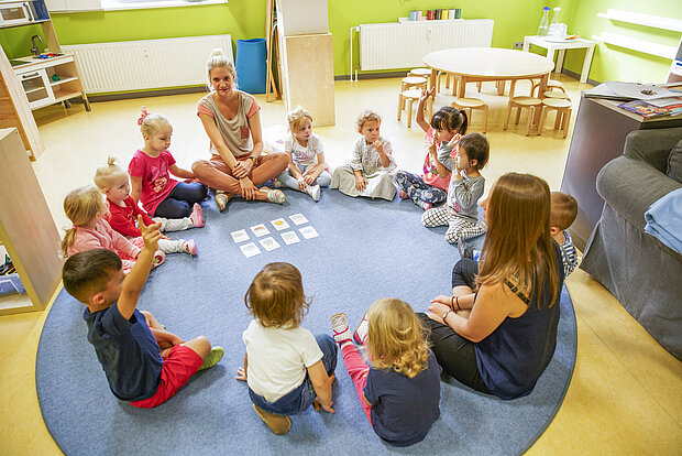 Kita Gruppenkinder sitzen im Morgenkreis in der Phorms Kita Hamburg und spielen