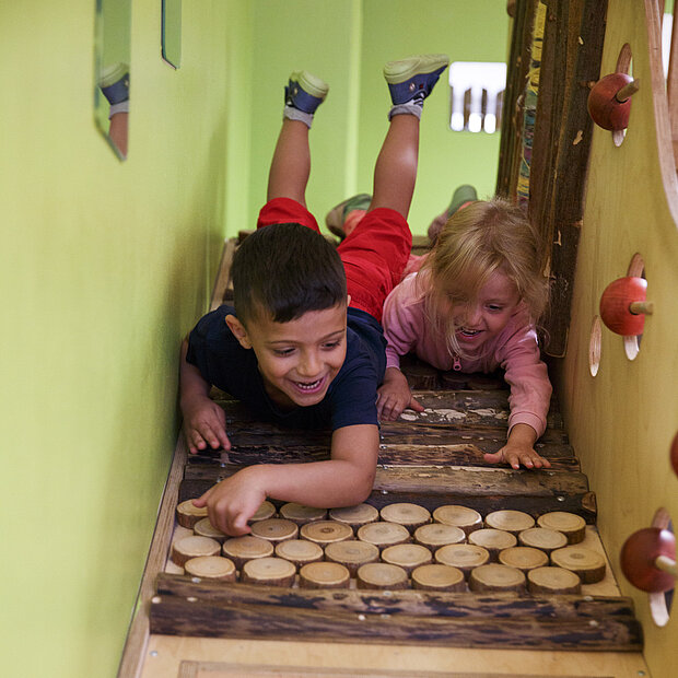 Zwei lächelnde Kinder spielen gemeinsam im Spielraum der Phorms Kita Hamburg