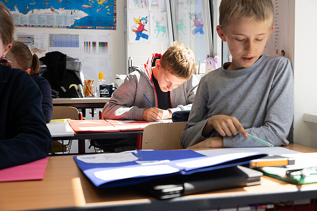 Schüler sitzen im Unterricht und bearbeiten Aufgaben im Phorms Gymnasium Hamburg