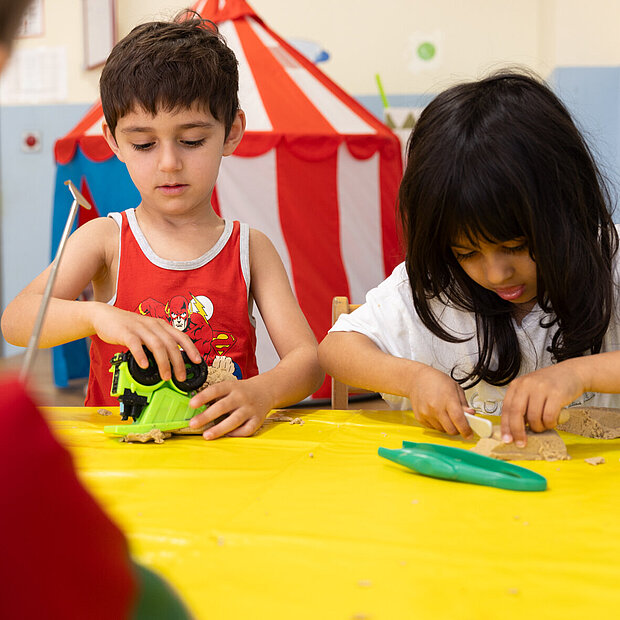 Zwei Kinder der Phorms Kita in Hamburg spielen am Tisch mit Knete in der Phorms Kita Hamburg