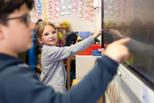 Zwei Kinder stehen am Smartboard der Klasse und lernen