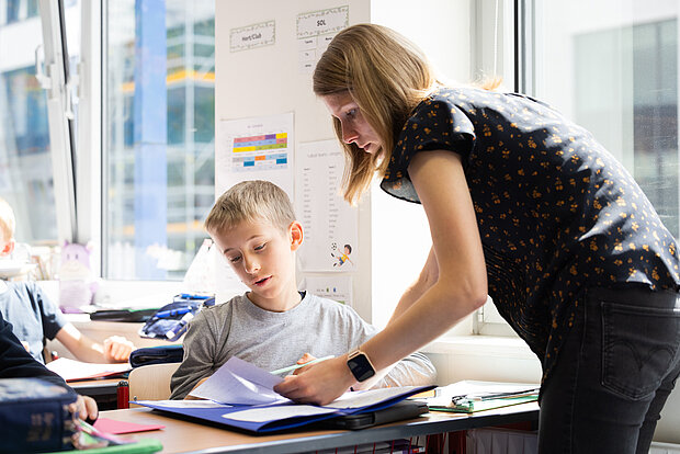 Eine Lehrerin erklärt einem Schüler eine Aufgabe während des Unterrichts im Phorms Gymnasium Hamburg