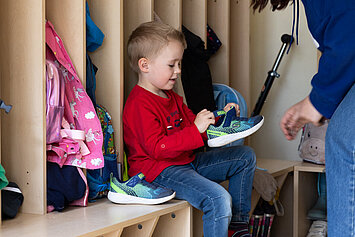 Phorms Hamburg Kita Kinder beim Schuhe Anziehen Kita-Kind zieht sich die Schuhe an in der Phorms Kita in Hamburg