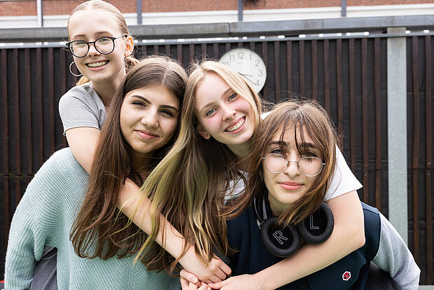 Vier Schülerinnen stehen gemeinsam lächelnd auf dem Schulhof des Phorms Gymnasiums Hamburg