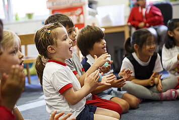 Phorms Hamburg Kita Kinder im Kreis mit Hühnerei in der Hand Eine Gruppe Kinder sitzen lächelnd mit einem Hühnerei in der Hand im Kreis in der Phorms Kita Hamburg