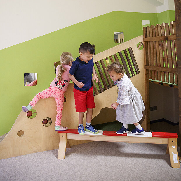 Drei Kinder spielen lächelnd gemeinsam im Spieleraum der Phorms Kita Hamburg