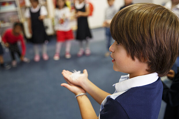 Kinder stehen im Kreis mit einer Feder auf der Hand in in der Phorms Reception Hamburg